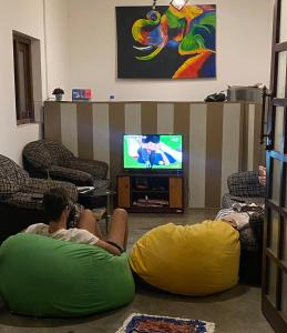 坦加拉Luaya Beach的两个人躺在客厅的地板上看电视