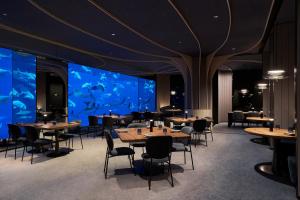 新加坡Resorts World Sentosa - Equarius Villas的一间带桌椅的餐厅和一个大型水族馆