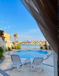 半月湾شاليه فخم مع مسبح وبحر خاص بالخبر的享有带两把椅子的游泳池的景色