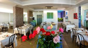里乔内Hotel Sorriso - molto più di una stella的中间设有种有鲜花的桌椅的餐厅