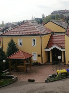 萨格勒布Studio apartman Jordanovac Rebro的黄色的房子,有红色的屋顶和凉亭