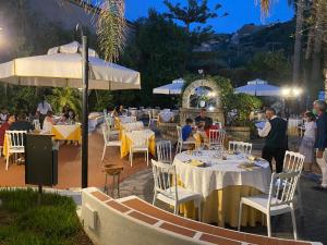 帕尔盖利亚第勒尼安海酒店的一间设有白色桌椅和遮阳伞的餐厅