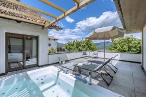 阿皮亚诺苏拉斯特拉达隆格霍夫阿西兹酒店的庭院内的热水浴池和遮阳伞