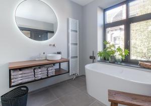 NuthB&B De Oude Dorpsslagerij的浴室配有白色浴缸和镜子