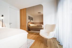 克拉尼斯卡戈拉Bor in Bor Luxury Apartment with sauna & garden - Kranjska Gora的卧室配有白色的床和白色椅子
