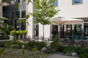 斯图加特Motel One Stuttgart-Feuerbach的庭院配有遮阳伞和桌椅。