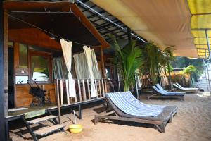 阿贡达Madhu Huts Agonda的一个带椅子的庭院和一个带棕榈树的房子