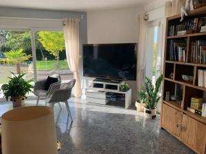 欧塞尔Magnifique Villa au cœur de l’Yonne的客厅配有平面电视和书架