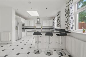 伦敦Park Royal Hububb Stay的厨房配有白色橱柜和黑色柜台凳