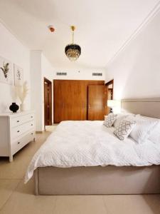 迪拜Spectacular Downtown Apartment T1-34的白色卧室配有一张大床和吊灯