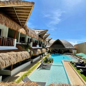 邦劳Bathala Resort的一个带游泳池和稻草遮阳伞的度假村
