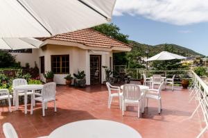维拉卡洛斯帕兹del Buen Ayre的庭院配有白色的桌椅和遮阳伞。
