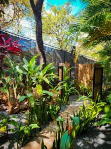 格兰德海滩Glamping Hotel Flor y Bambu的花园种有绿色植物,设有围栏