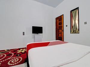 占碑市OYO 92054 Gala Residence的一间白色卧室,配有床和电视