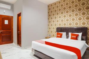 棉兰SUPER OYO Capital O 92066 Papakoel Hotel & Cafe的卧室配有带红色枕头的大型白色床