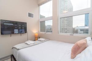 芝加哥McCormick Place 2br-2ba with Optional Parking, Patio, Gym access for 6 guests的一间卧室设有一张床、电视和窗户