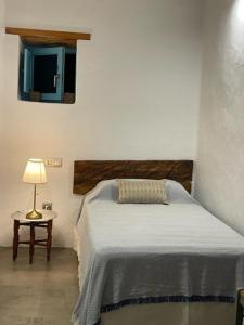 瓜蒂萨PETITE CASA LEONCIA的一间卧室配有一张床和一张带台灯的桌子