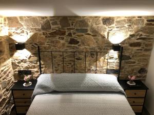 拉科鲁尼亚A Caseta的一间卧室设有石墙、一张床和两盏灯。