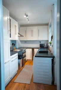 纽尼顿Comfortable equipped House in Nuneaton sleeps5 with FREE parking的厨房配有白色橱柜和黑色台面