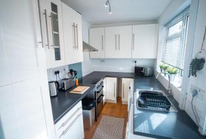 纽尼顿Comfortable equipped House in Nuneaton sleeps5 with FREE parking的厨房配有白色橱柜和黑色台面