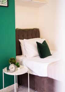 纽尼顿Comfortable equipped House in Nuneaton sleeps5 with FREE parking的一张带绿色和白色枕头的床和一张桌子