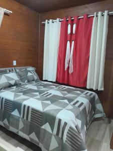 圣弗朗西斯科-迪保拉Cabanas dos Pinheiros的一间卧室配有床和红色及白色窗帘
