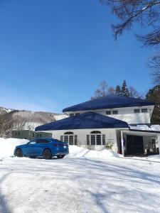 白马村Luna Lodge的停在房子前面的蓝色汽车
