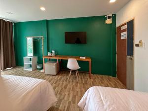 素叻普乐佩琪酒店的客房设有书桌和绿色的墙壁。
