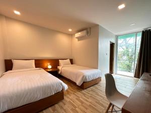 素叻普乐佩琪酒店的一间卧室设有两张床、一张桌子和一个窗口。