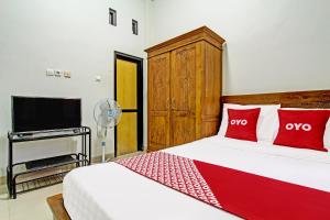 GlagahOYO 92071 Yusman Homestay Syariah的一间卧室配有一张带红色枕头的床和一台电视。