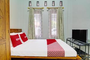 GlagahOYO 92071 Yusman Homestay Syariah的一间卧室配有一张带红色枕头的床和电视。