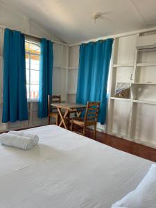 小玉米岛Christina's Guest House OFFICIAL的一间卧室配有一张床、一张桌子和蓝色窗帘