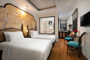 河内La Passion Hanoi Hotel & Apartment的酒店客房配有两张床和一张书桌