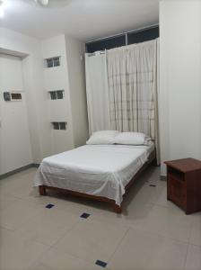 伊基托斯Emmanuel&Cavita的卧室配有白色的床和桌子