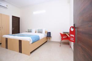 古尔冈OYO Dlf Cyber City Near Aravali Biodiversity Park的一间卧室配有一张床和一张红色椅子