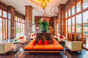 芭堤雅市中心Centara Nova Hotel Pattaya的大堂设有橙色的沙发和花瓶