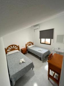 隆达Hostal La Campiña的酒店客房设有两张床和一张桌子。
