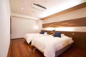 天童市天童酒店的配有白色床单和蓝色枕头的酒店客房内的两张床