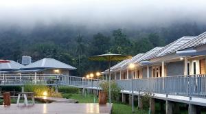 湄宏颂Jeerang Countryside Resort的甲板上带遮阳伞的房子