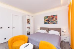 杜布罗夫尼克佩拉格罗别墅公寓的一间卧室配有一张床和两张橙色椅子