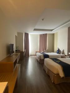 永隆Khách sạn Sài Gòn Vĩnh Long的酒店客房设有两张床和电视。