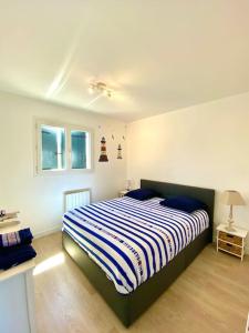 帕克斯港Magnifique maison avec piscine的一间卧室配有一张带蓝白条纹毯子的床