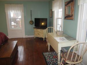 Granville FerryGrand Oak Manor Bed and Breakfast的客厅配有电视和带桌子的书桌。