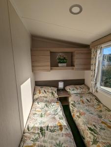 韦茅斯Sleeps 6 Modern and bright Caravan Littlesea Haven Weymouth的小房间设有两张床和窗户