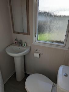 韦茅斯Sleeps 6 Modern and bright Caravan Littlesea Haven Weymouth的一间带水槽和卫生间的浴室以及窗户。