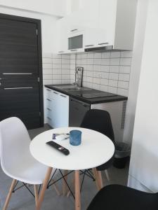 依诺罗达Aiolos Blu Luxury Apartments的小厨房配有白色的桌子和椅子