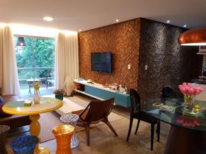 马塞约Villas do Pratagy resort Maceió próximo praia的客厅配有桌子,墙上配有电视