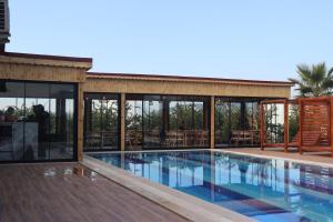 塞尔丘克Mandalin Glamping的一座带游泳池和玻璃墙的房屋