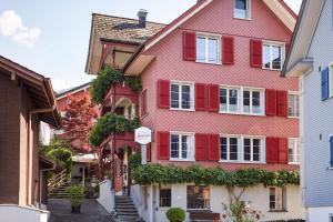 贝肯里德施鲁塞尔精品酒店的街上有红色百叶窗的粉红色房子