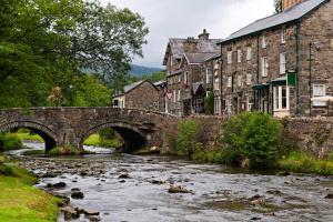 圣亚萨The North Wales Gathering - Hot Tub & Sleeps Up To 16的一座古老的石桥,在镇上的河流上